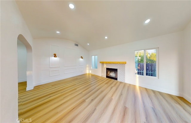 unfurnished living room with vaulted ceiling, light hardwood / wood-style floors, and a fireplace