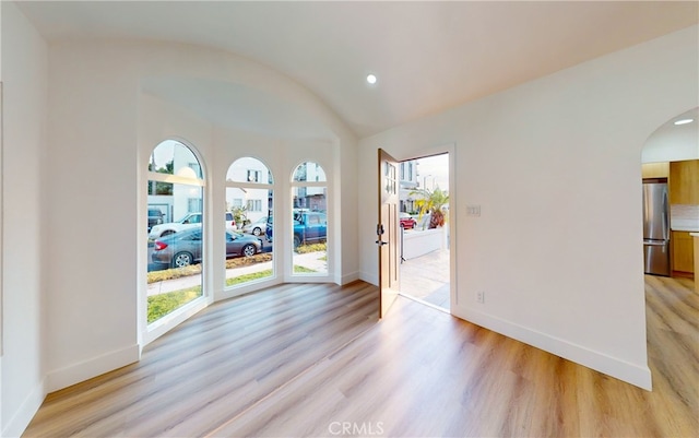 unfurnished room with lofted ceiling and light hardwood / wood-style floors