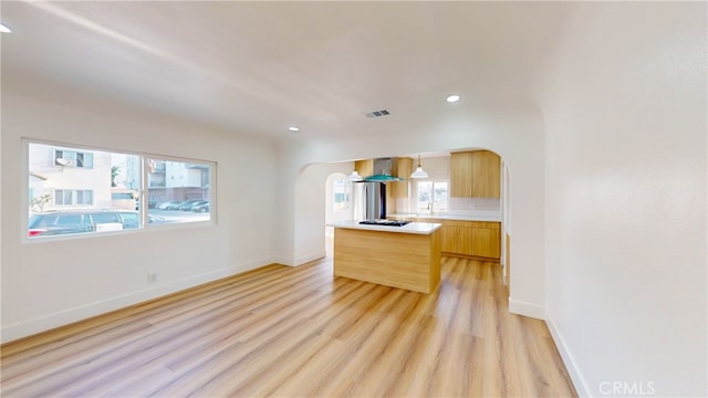 kitchen featuring hanging light fixtures, a kitchen island, light brown cabinets, island exhaust hood, and light hardwood / wood-style flooring