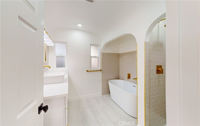 bathroom with vanity, tile walls, hardwood / wood-style floors, and a bath