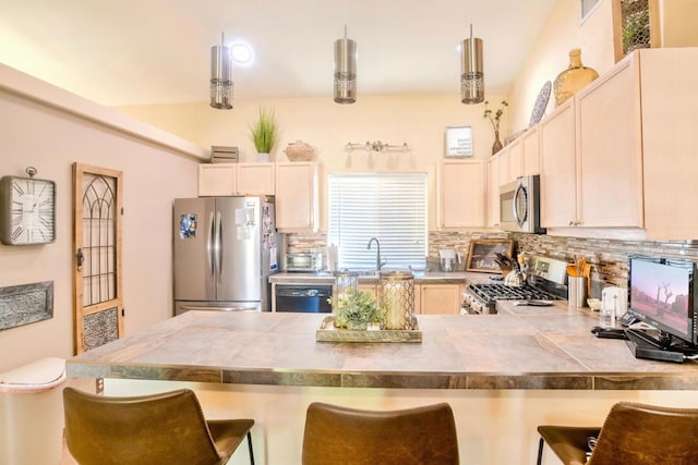 kitchen with appliances with stainless steel finishes, tasteful backsplash, hanging light fixtures, and a breakfast bar area