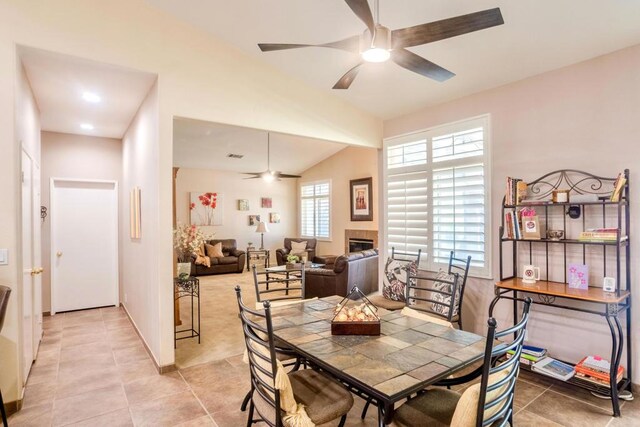 tiled dining room featuring ceiling fan, a wealth of natural light, and a tiled fireplace