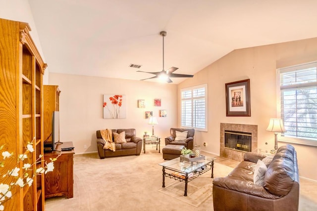 carpeted living room with vaulted ceiling, ceiling fan, and a tiled fireplace