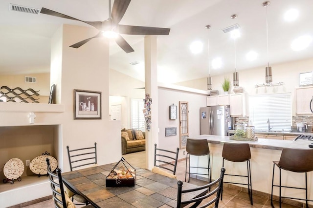 dining space featuring sink, light tile patterned floors, and lofted ceiling