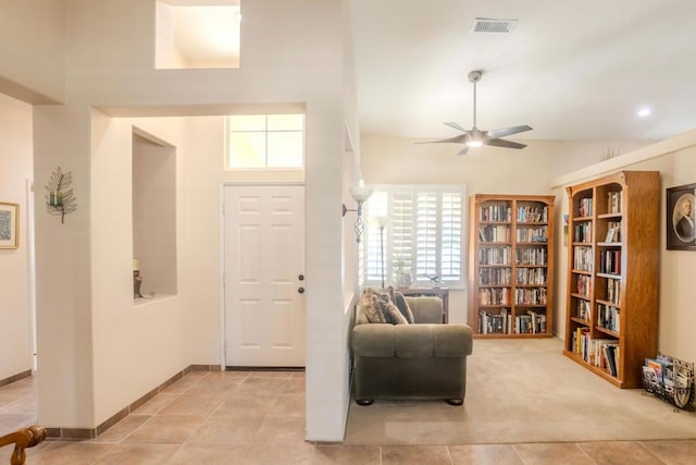 foyer entrance featuring a towering ceiling, light colored carpet, and ceiling fan