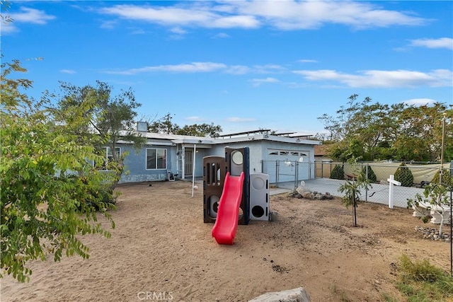 ranch-style house featuring concrete driveway, fence, a garage, roof mounted solar panels, and stucco siding