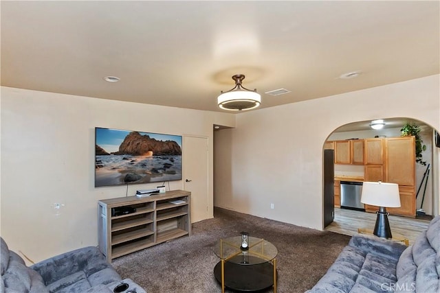 living room with arched walkways, visible vents, and carpet flooring