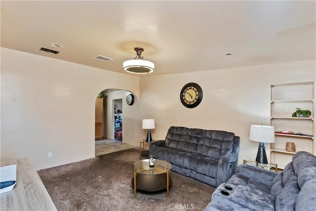 carpeted living area featuring visible vents and arched walkways