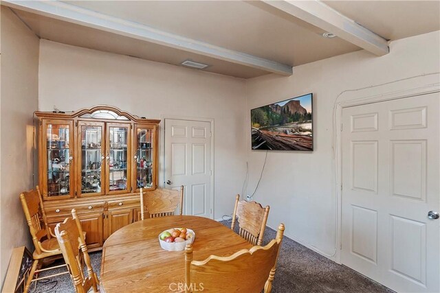 carpeted dining area with beamed ceiling, baseboards, and visible vents