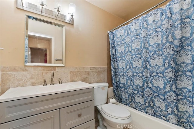 full bath with wainscoting, vanity, shower / tub combo with curtain, tile walls, and toilet