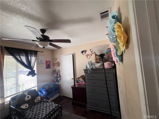 bedroom with ceiling fan, dark wood-type flooring, and a textured ceiling