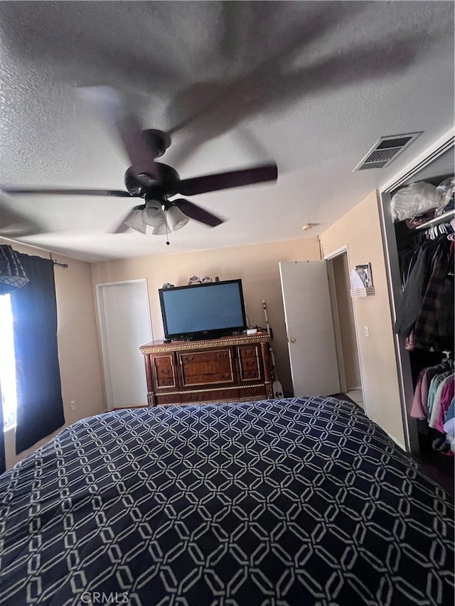 carpeted bedroom featuring ceiling fan, a textured ceiling, and a closet