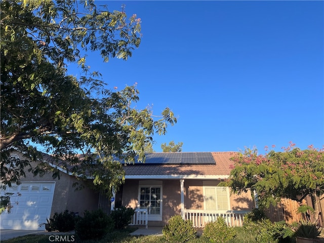 single story home with a garage and solar panels