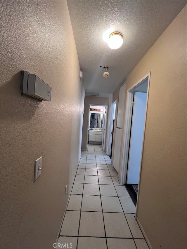 hallway featuring a textured ceiling and light tile patterned floors