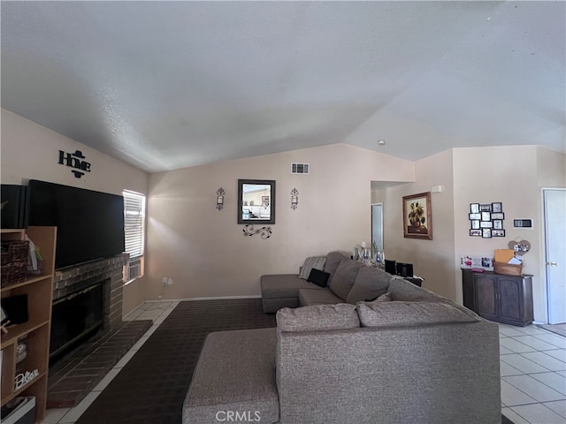 living room featuring a brick fireplace, vaulted ceiling, and light tile patterned flooring