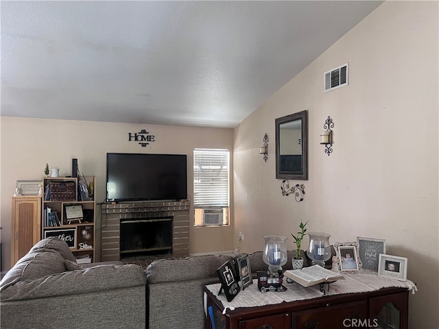 living room featuring cooling unit, lofted ceiling, and a brick fireplace