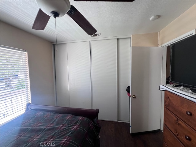 bedroom featuring ceiling fan, a textured ceiling, a closet, and dark wood-type flooring