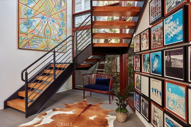 stairway with tile patterned floors and a high ceiling