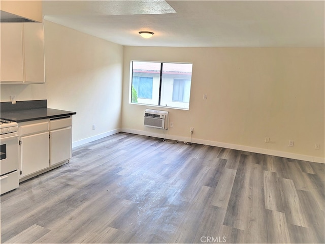 kitchen with light hardwood / wood-style flooring, white cabinetry, white range oven, and a wall mounted air conditioner