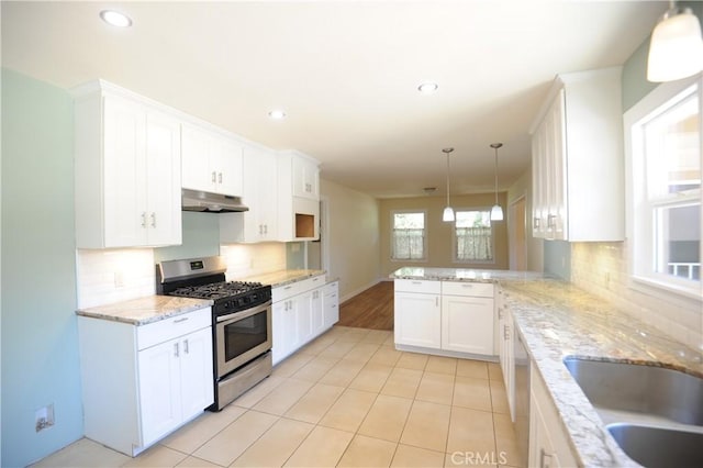 kitchen with appliances with stainless steel finishes, white cabinetry, kitchen peninsula, pendant lighting, and backsplash