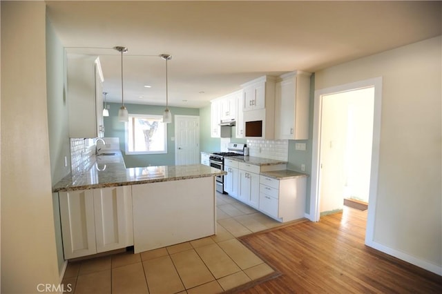 kitchen with kitchen peninsula, white cabinets, stainless steel range with gas cooktop, and tasteful backsplash