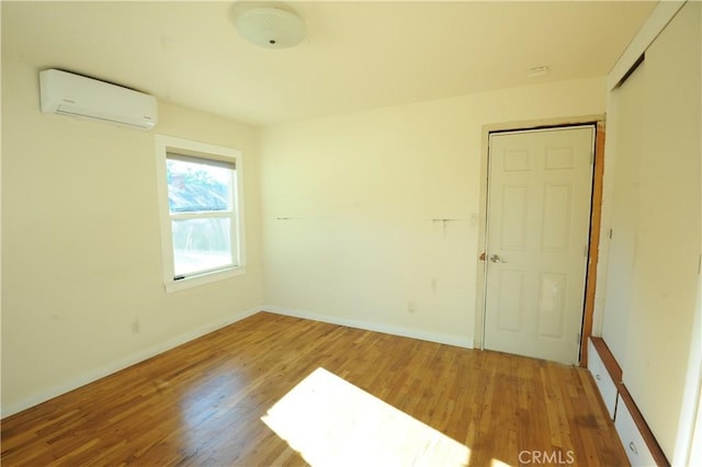 unfurnished room featuring hardwood / wood-style floors and a wall unit AC