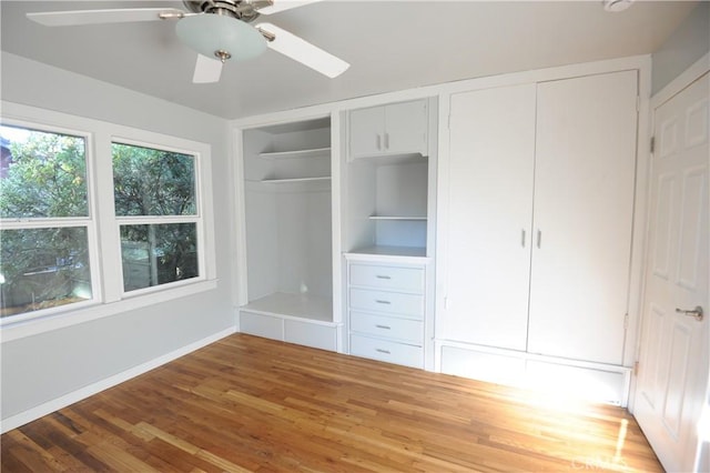 unfurnished bedroom with hardwood / wood-style floors, ceiling fan, and multiple closets