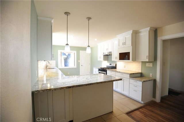 kitchen with pendant lighting, white cabinetry, sink, kitchen peninsula, and stainless steel gas range oven