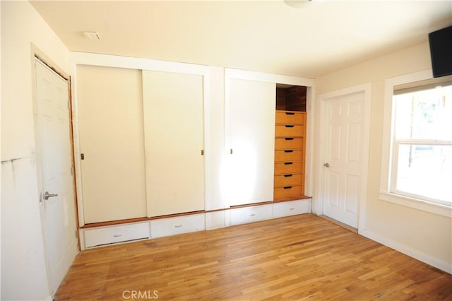 unfurnished bedroom featuring light hardwood / wood-style floors and two closets