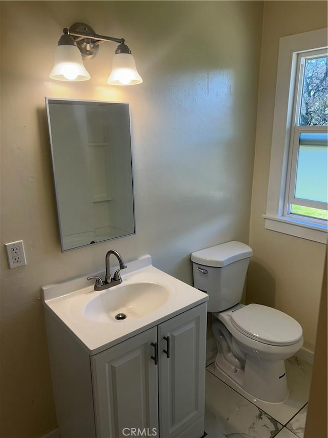 bathroom with plenty of natural light, toilet, and vanity