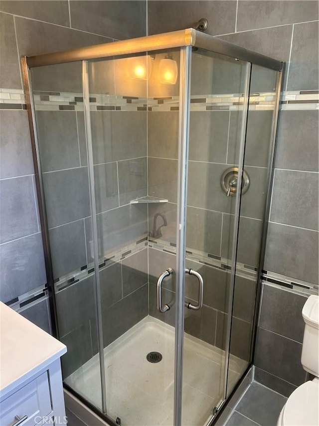 bathroom with tile patterned floors, an enclosed shower, vanity, and toilet