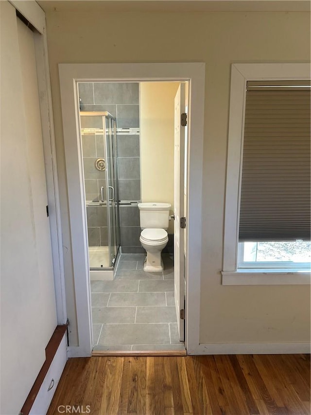 bathroom featuring toilet, hardwood / wood-style floors, and a shower with door