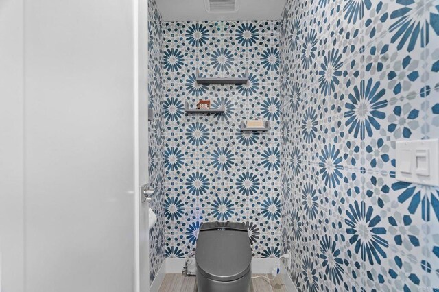 bathroom featuring toilet and tile walls