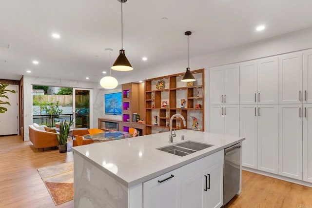 kitchen featuring white cabinetry, dishwasher, sink, hanging light fixtures, and a kitchen island with sink