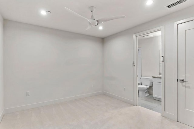 unfurnished bedroom featuring connected bathroom, light colored carpet, and ceiling fan