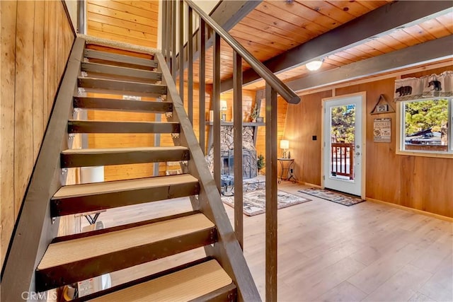 stairs featuring beamed ceiling, hardwood / wood-style flooring, wood ceiling, and wood walls