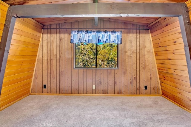 carpeted spare room featuring wooden walls and lofted ceiling with beams