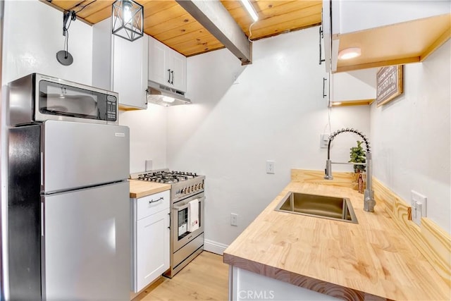 kitchen featuring pendant lighting, sink, butcher block countertops, stainless steel appliances, and white cabinets