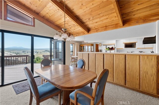 carpeted dining room featuring wooden ceiling, a chandelier, a mountain view, and vaulted ceiling with beams