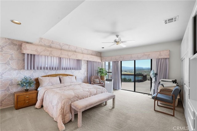 bedroom featuring a water view, access to exterior, light carpet, and ceiling fan