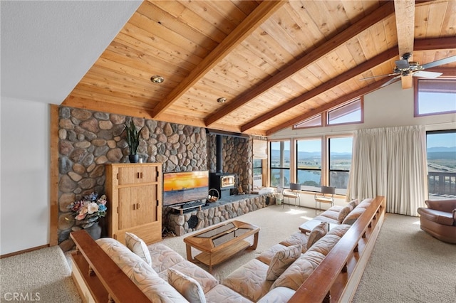 carpeted living room with ceiling fan, beam ceiling, a wood stove, high vaulted ceiling, and wooden ceiling