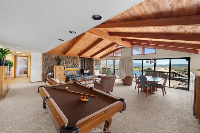 recreation room with a water view, lofted ceiling with beams, light carpet, and a wood stove