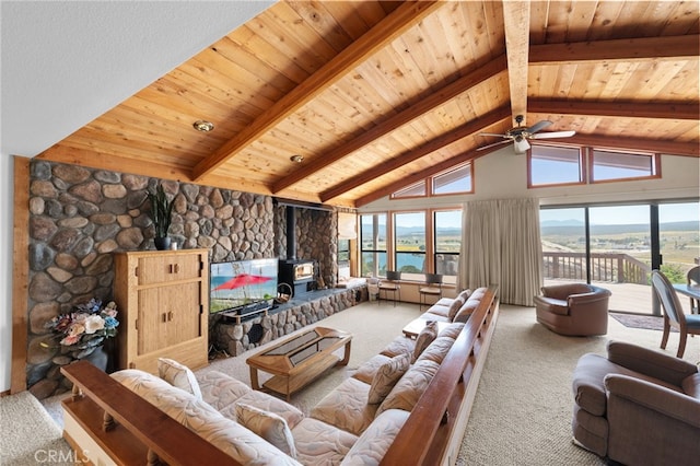 carpeted living room featuring wood ceiling, beamed ceiling, ceiling fan, a wood stove, and high vaulted ceiling