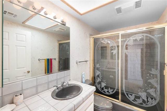 bathroom with a shower with door, toilet, vanity, and tasteful backsplash