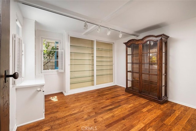 unfurnished room with rail lighting and dark wood-type flooring