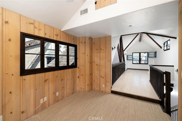 bonus room with wooden walls, light hardwood / wood-style flooring, a wealth of natural light, and lofted ceiling