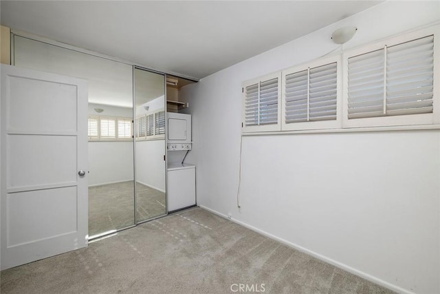 unfurnished bedroom with light colored carpet, stacked washer and dryer, and a closet