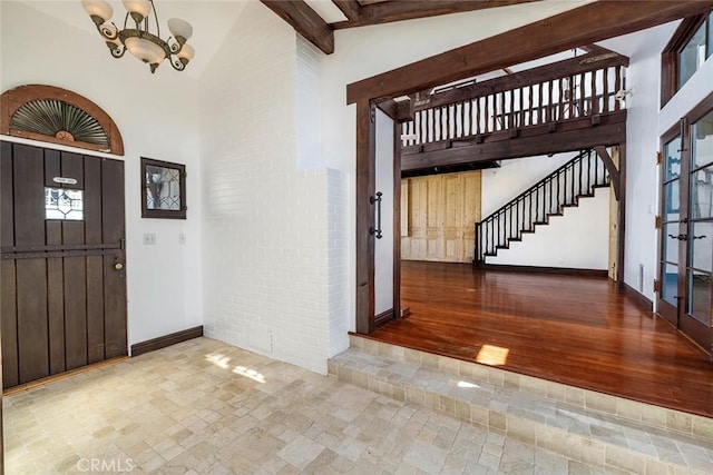 entryway featuring hardwood / wood-style floors, a notable chandelier, beamed ceiling, and high vaulted ceiling