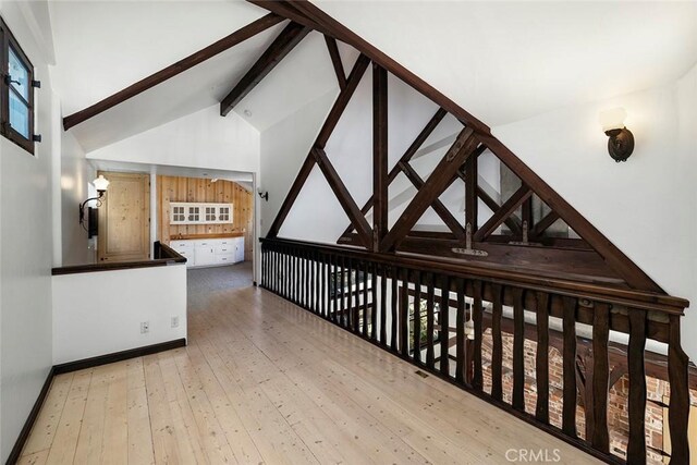 hall featuring lofted ceiling with beams and light hardwood / wood-style flooring