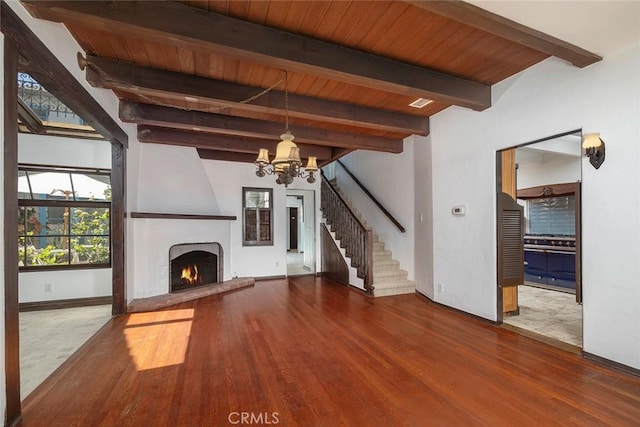 unfurnished living room featuring a chandelier, wood-type flooring, a brick fireplace, and wood ceiling